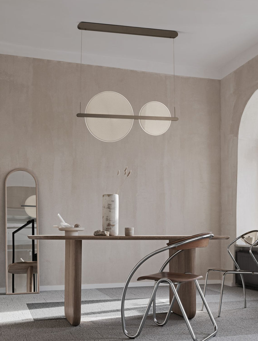Suspension marron à deux disques lumineux installée au-dessus d'une table de salle à manger