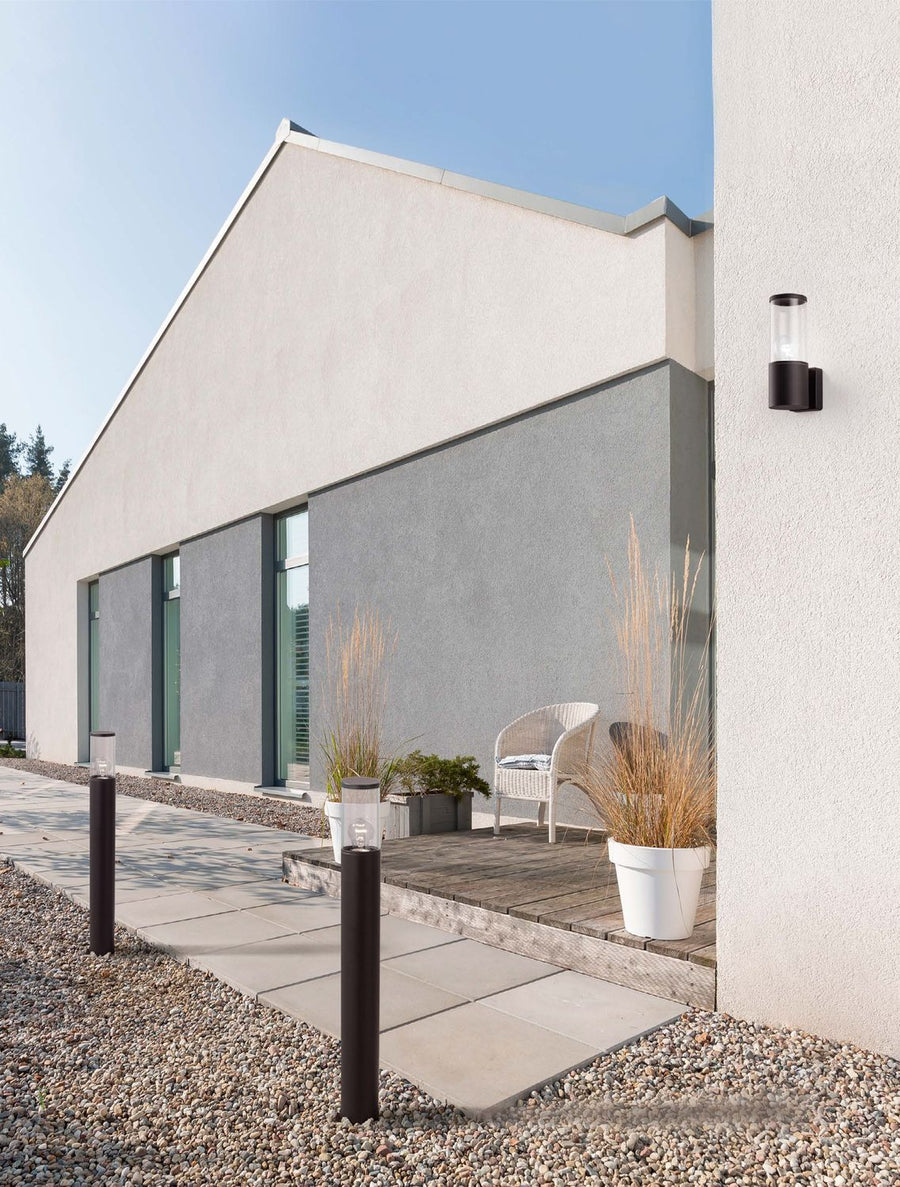 Mise en ambiance extérieure : deux bornes et une applique murale devant une maison moderne