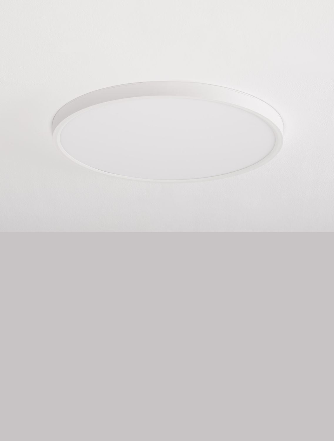Plafonnier rond blanc éteint, posé au ras d'un plafond blanc mat