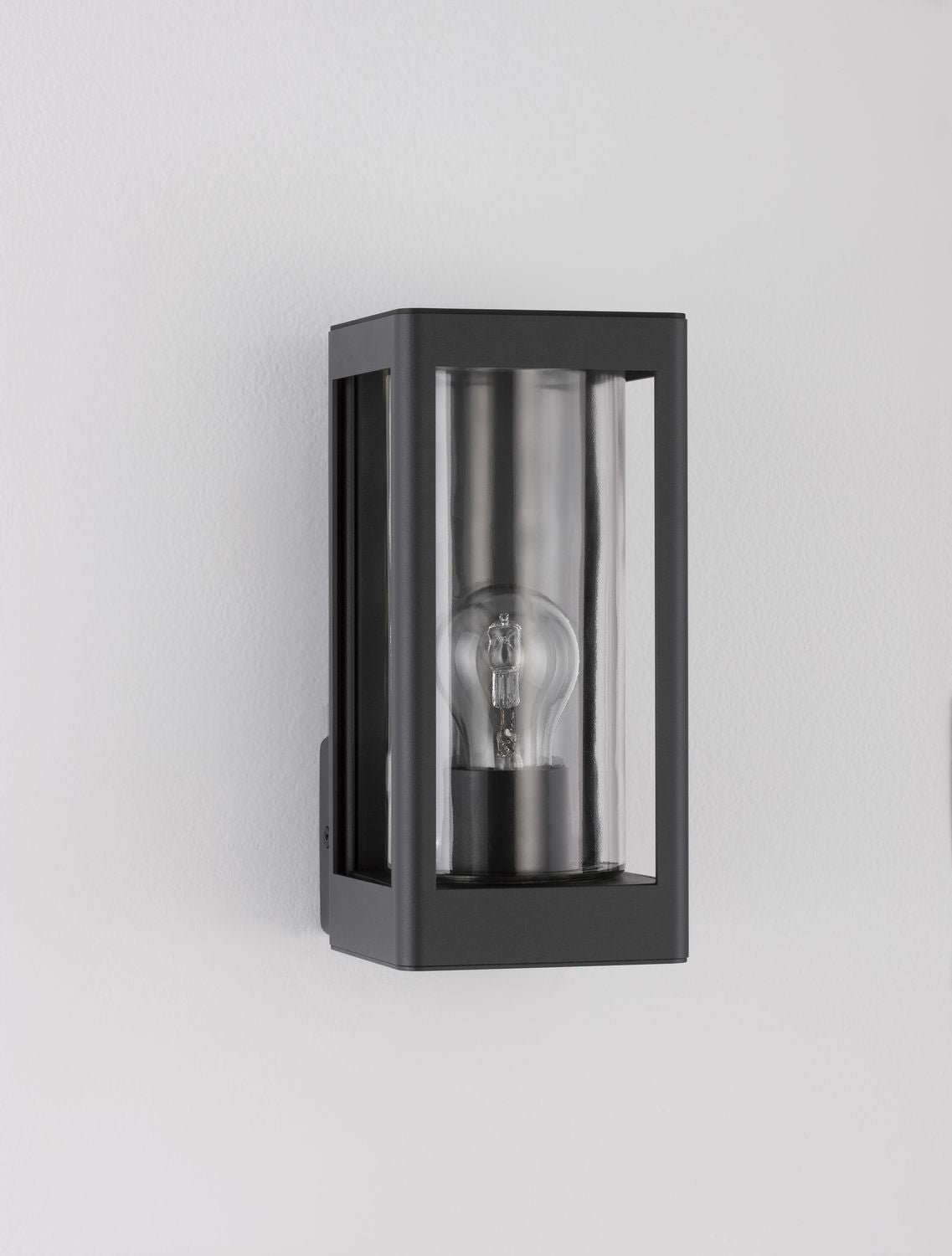 Vue de trois quarts de l'applique fixée sur un mur blanc, ampoule visible