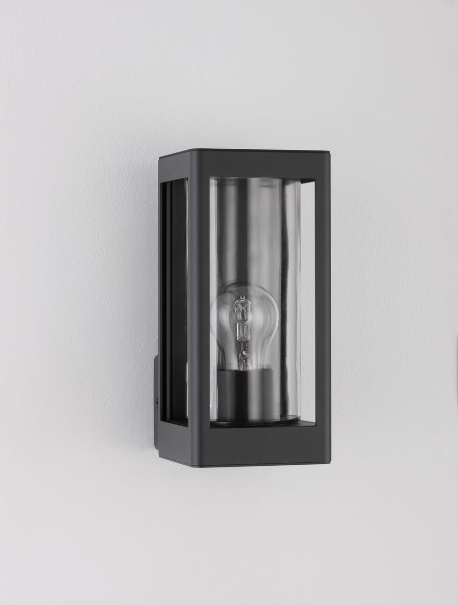 Vue de trois quarts de l'applique fixée sur un mur blanc, ampoule visible