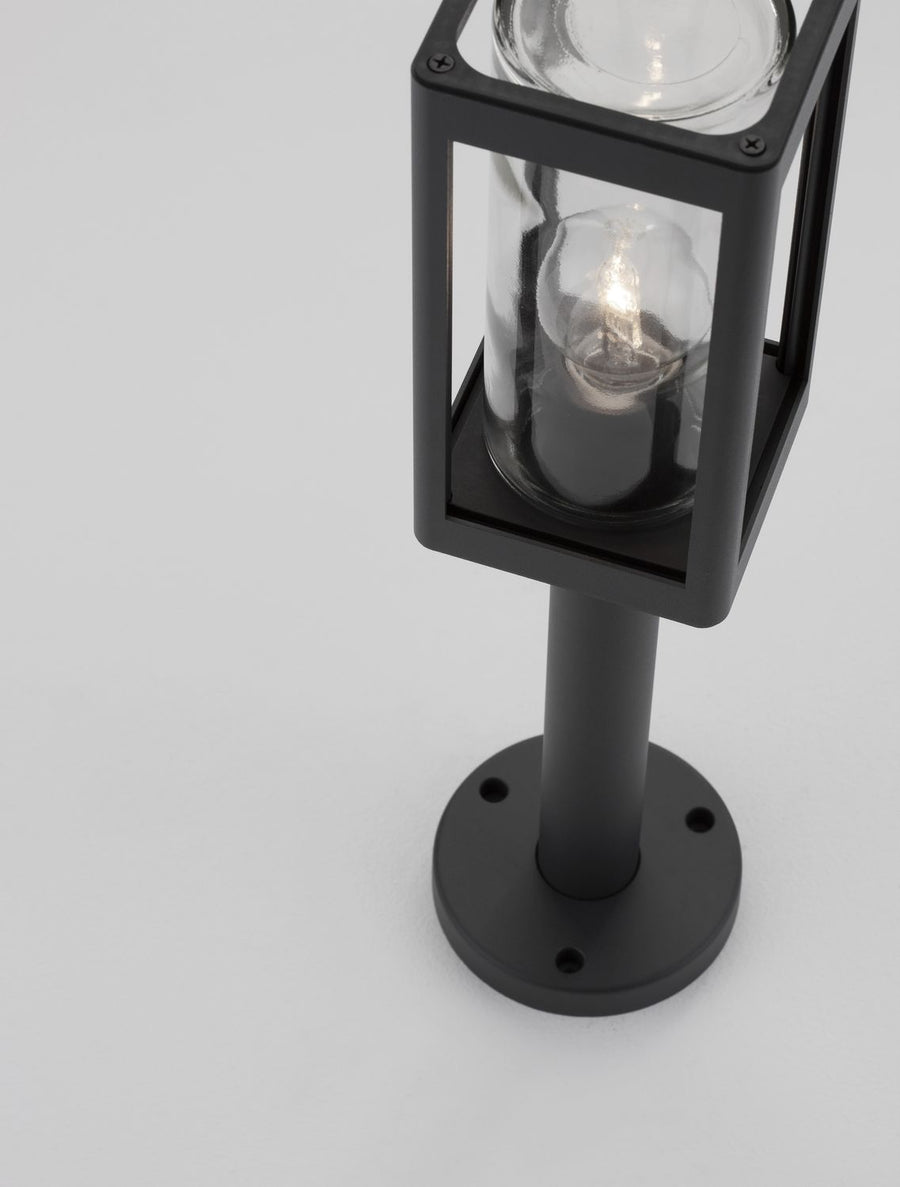 Gros plan sur la tête du luminaire, ampoule allumée derrière le verre transparent.