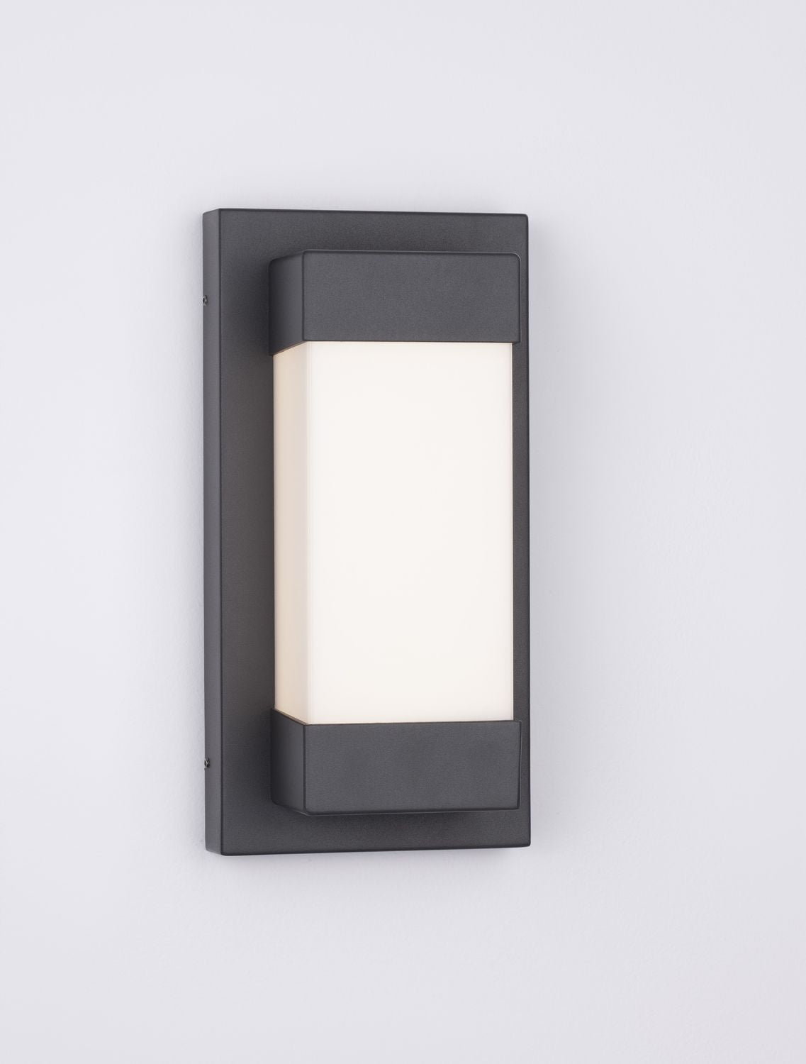 Applique murale noire allumée, diffuseur blanc diffusant une lumière chaude.