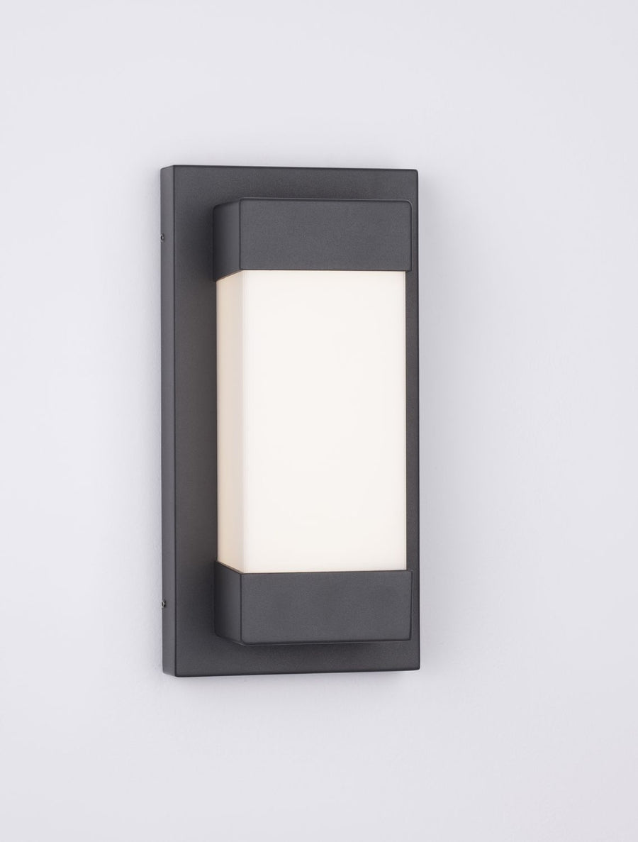 Applique murale noire allumée, diffuseur blanc diffusant une lumière chaude.