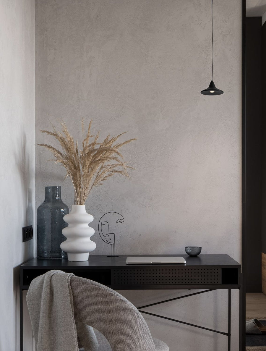 Suspension noire allumée au-dessus d'un bureau, décor intérieur épuré et minéral