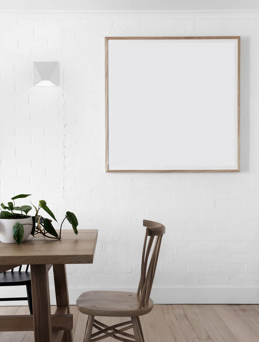Applique murale blanche allumée sur mur de briques, table et chaise en bois