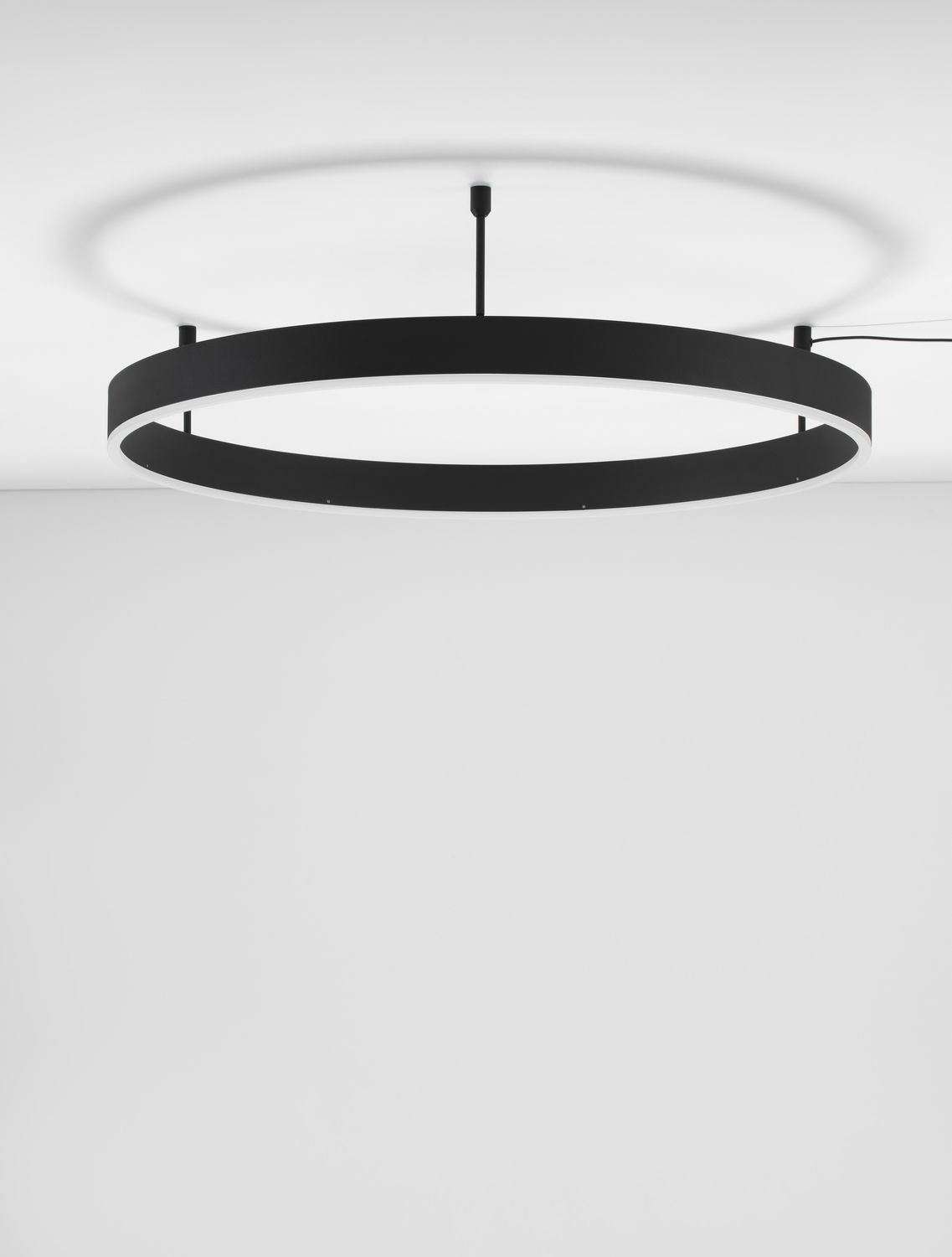 Plafonnier anneau noir de face, diffusant une lumière blanche sur le plafond
