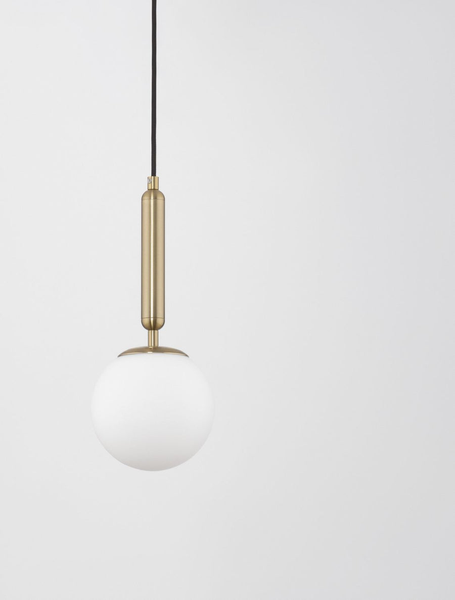 Gros plan sur la tige cylindrique dorée et le globe de verre blanc suspendu.