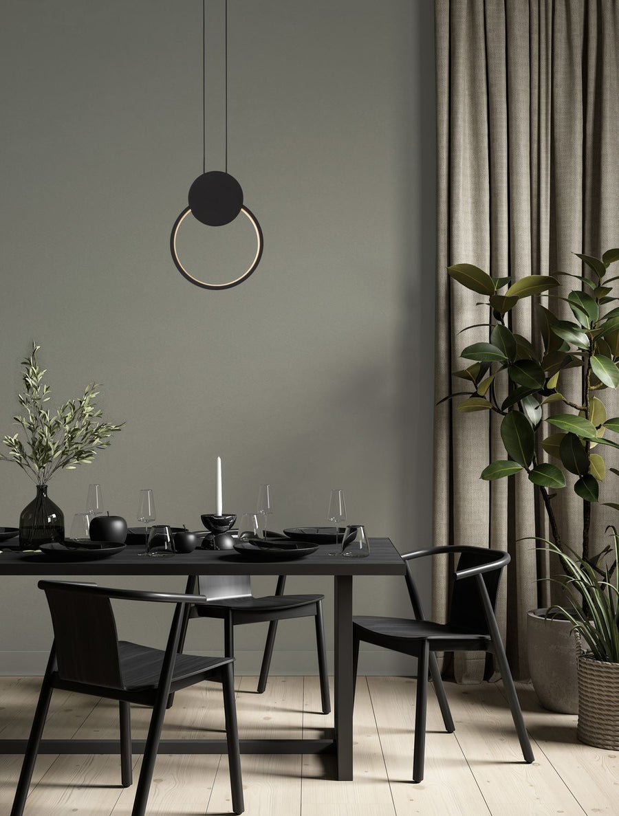 Suspension noire allumée au-dessus d'une table à manger dans un intérieur contemporain