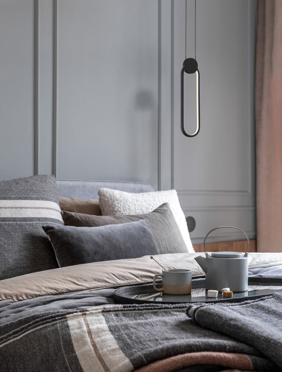 Suspension noire allumée au-dessus d'un lit garni de coussins et d'un plateau de thé