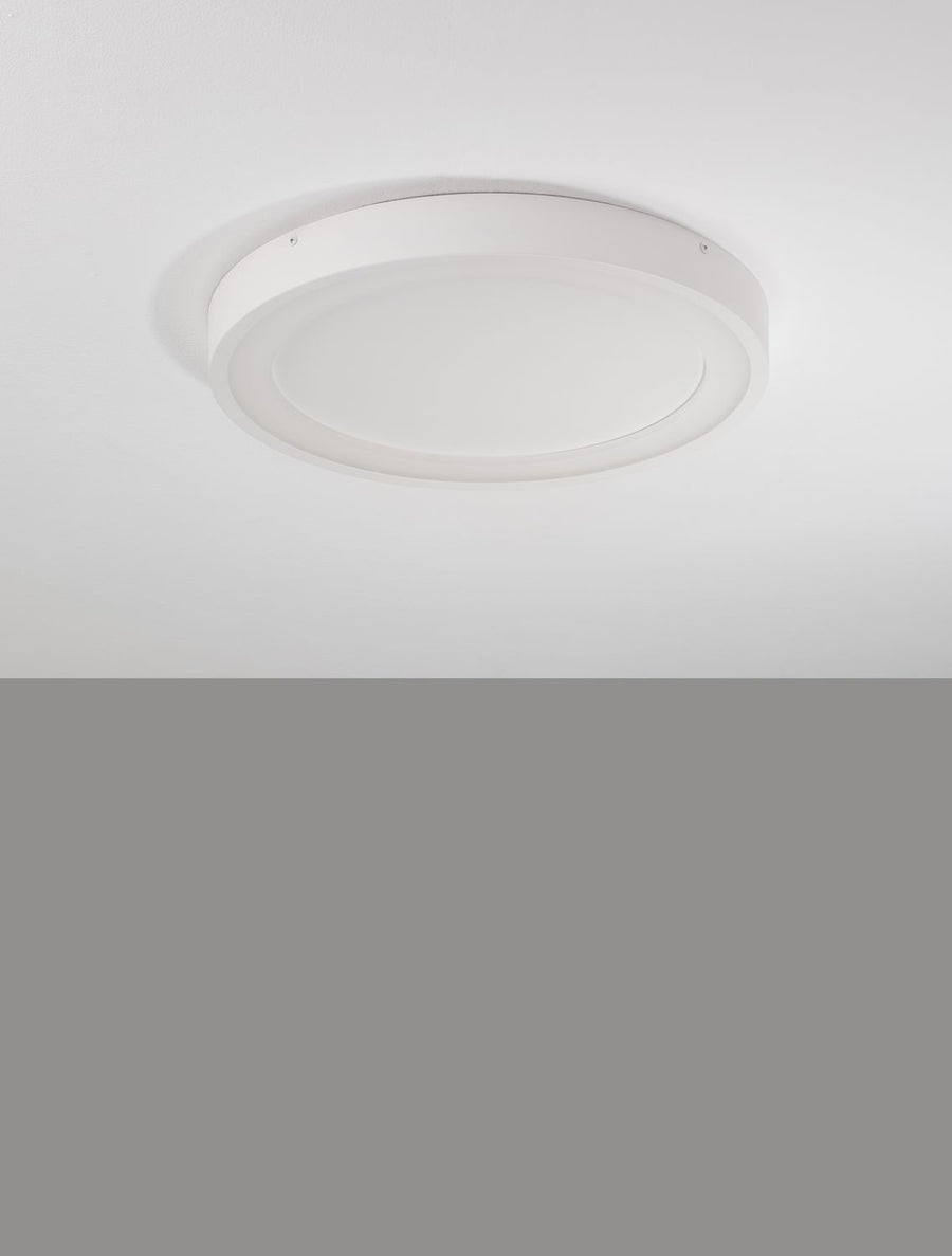 Plafonnier blanc éteint au plafond, diffuseur opalin et cerclage fin visible