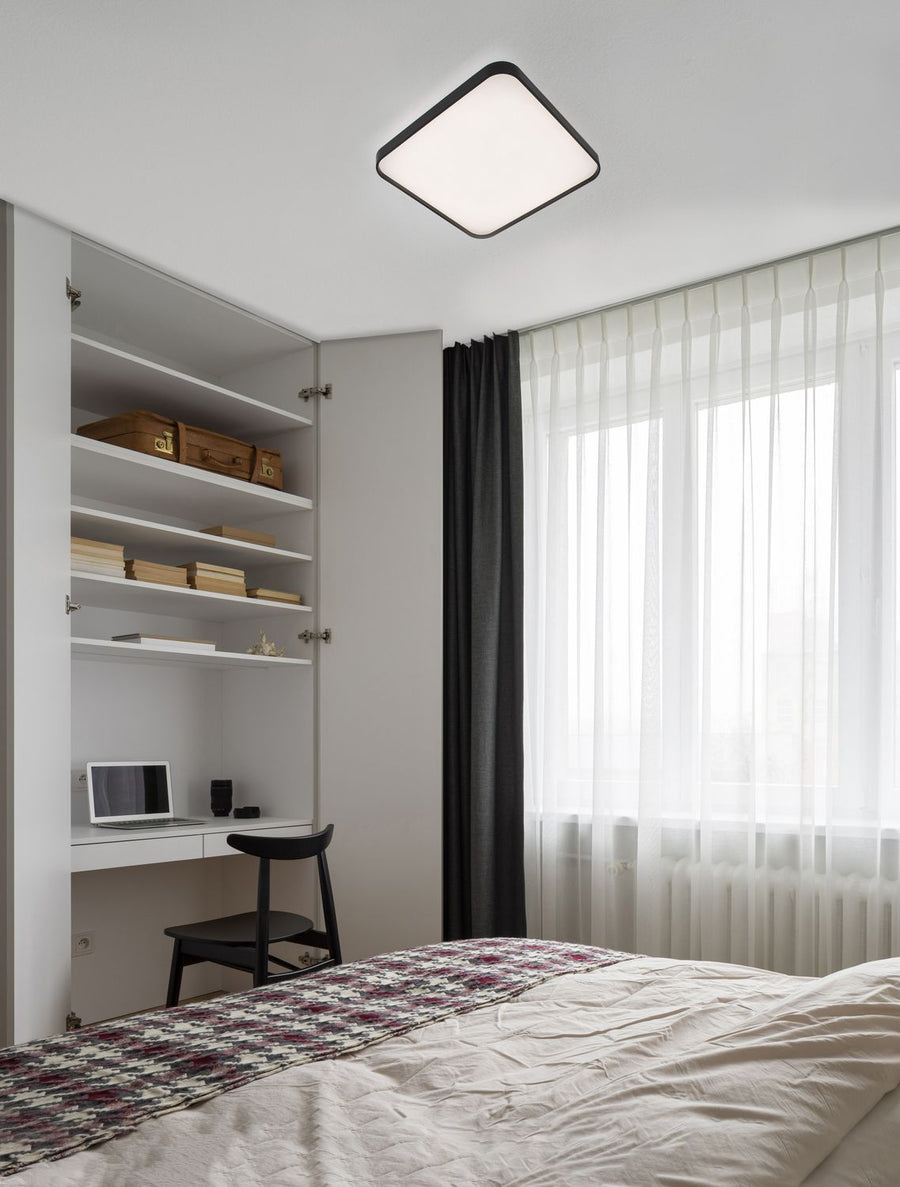 Plafonnier carré noir et blanc installé au plafond d'une chambre meublée