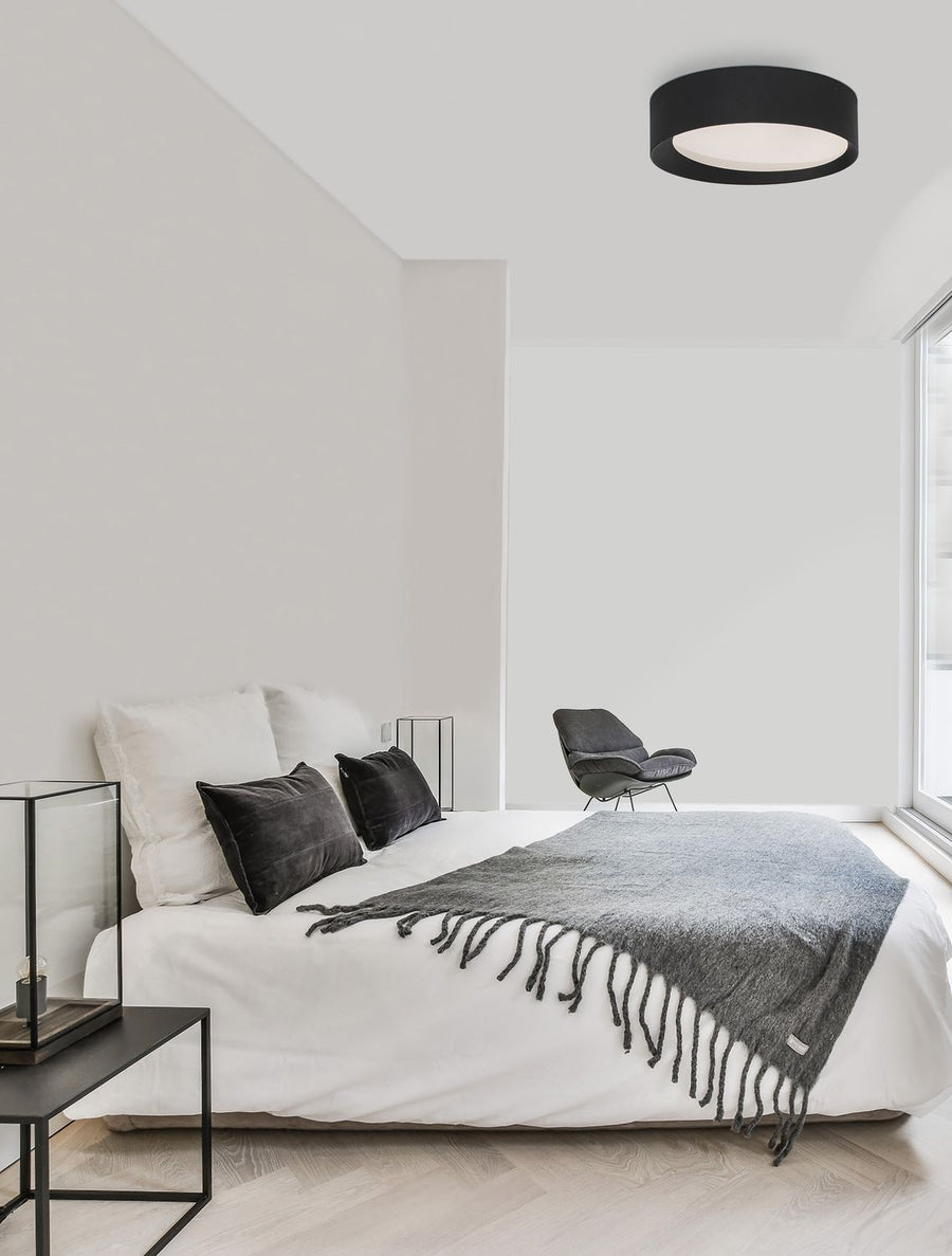 Plafonnier noir allumé au plafond d'une chambre blanche minimaliste