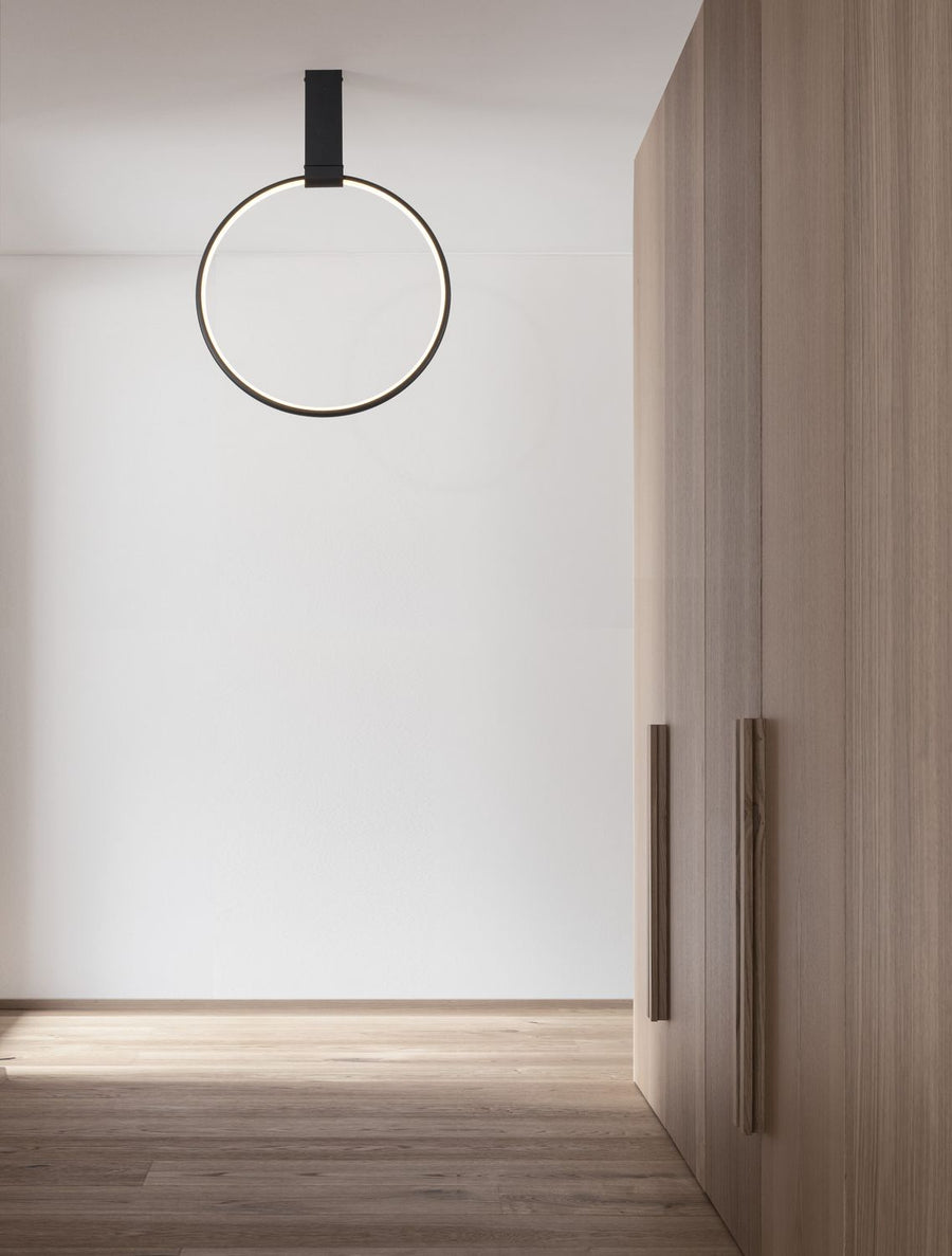 Suspension anneau noire allumée dans une pièce claire avec armoire en bois