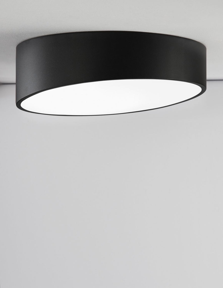 Plafonnier fixé au plafond clair, vu de biais, diffuseur blanc lumineux