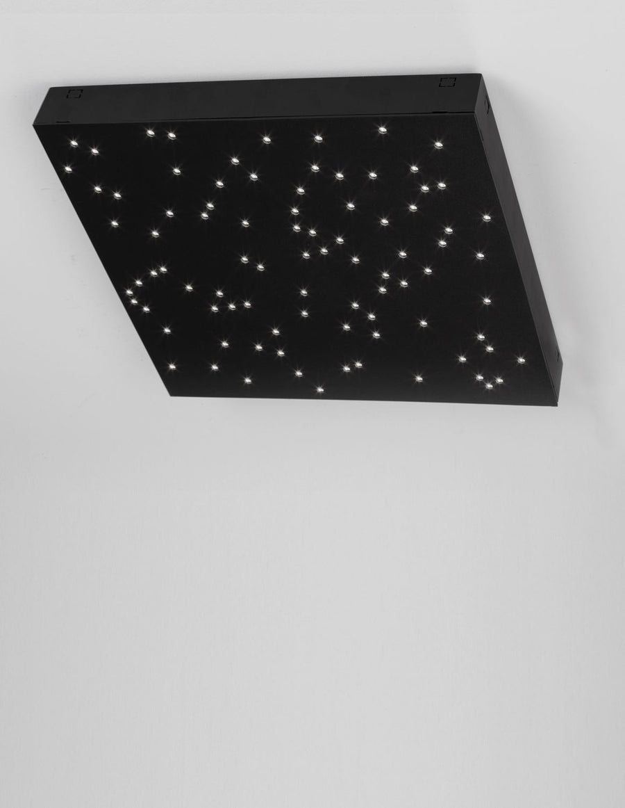 Plafonnier noir allumé au plafond, diffusant une multitude de petits points lumineux.