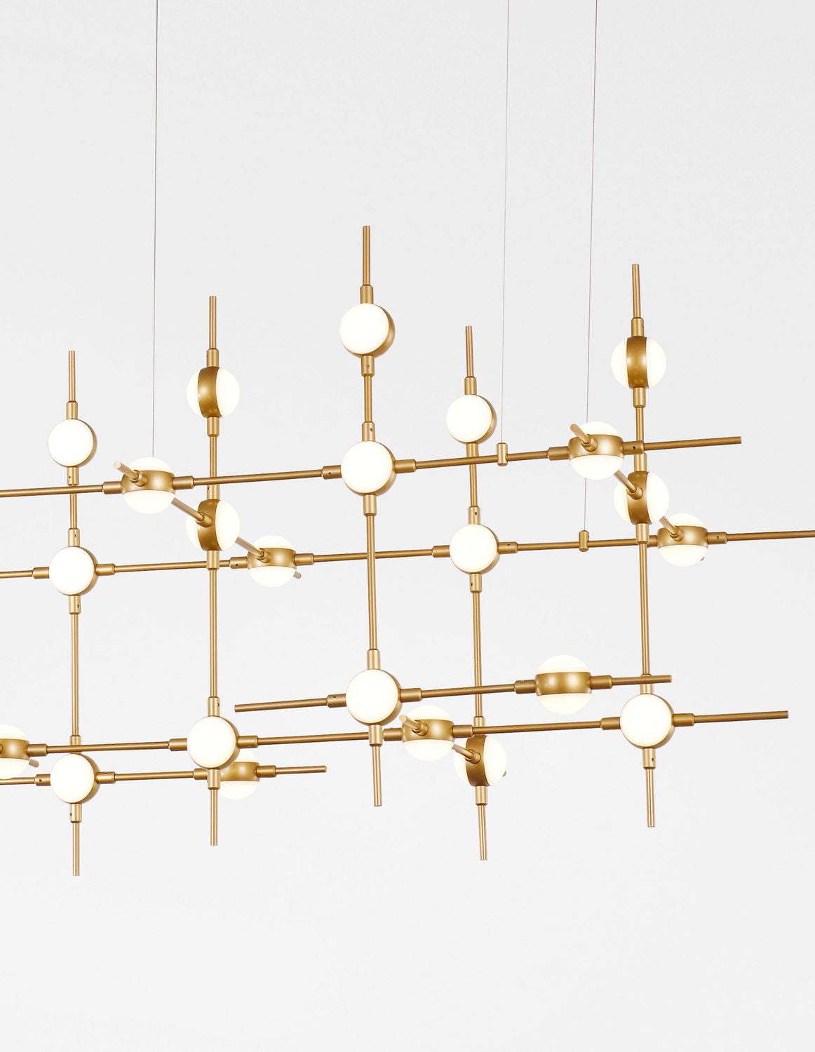 Détail rapproché de la structure dorée et des globes blancs suspendus, lignes entrecroisées.