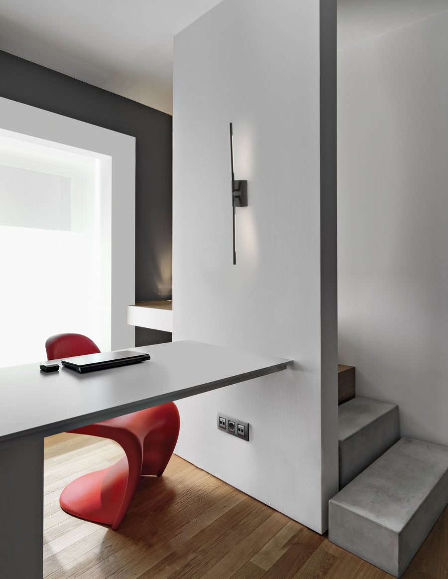 Applique murale noire allumée fixée sur un mur blanc au-dessus d'un bureau