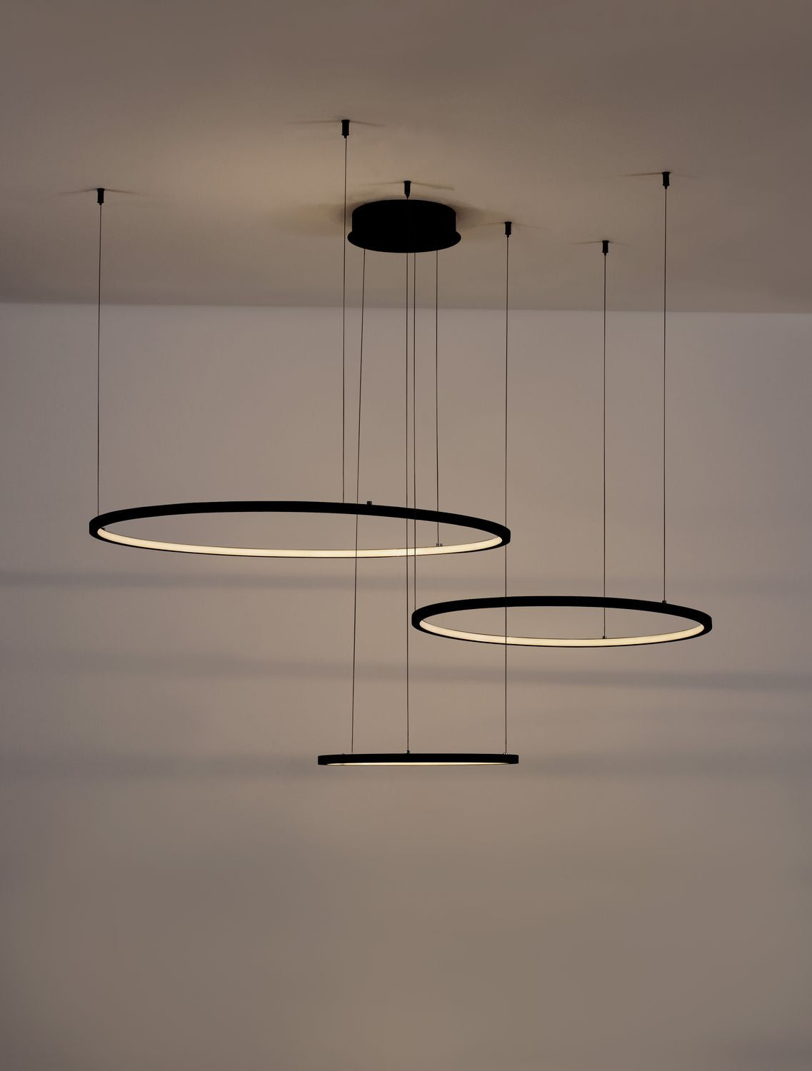 Luminaire allumé dans une pièce sombre, halo lumineux des anneaux au plafond