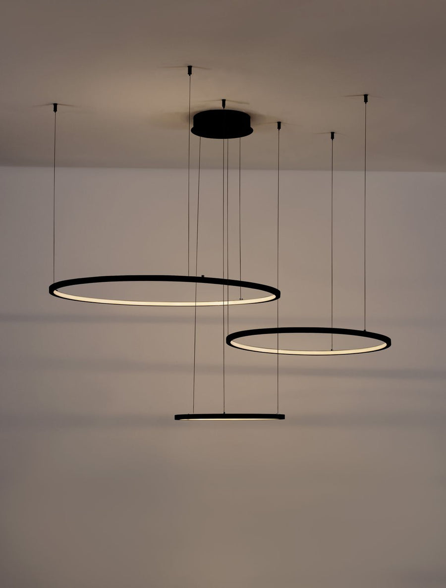 Luminaire allumé dans une pièce sombre, halo lumineux des anneaux au plafond