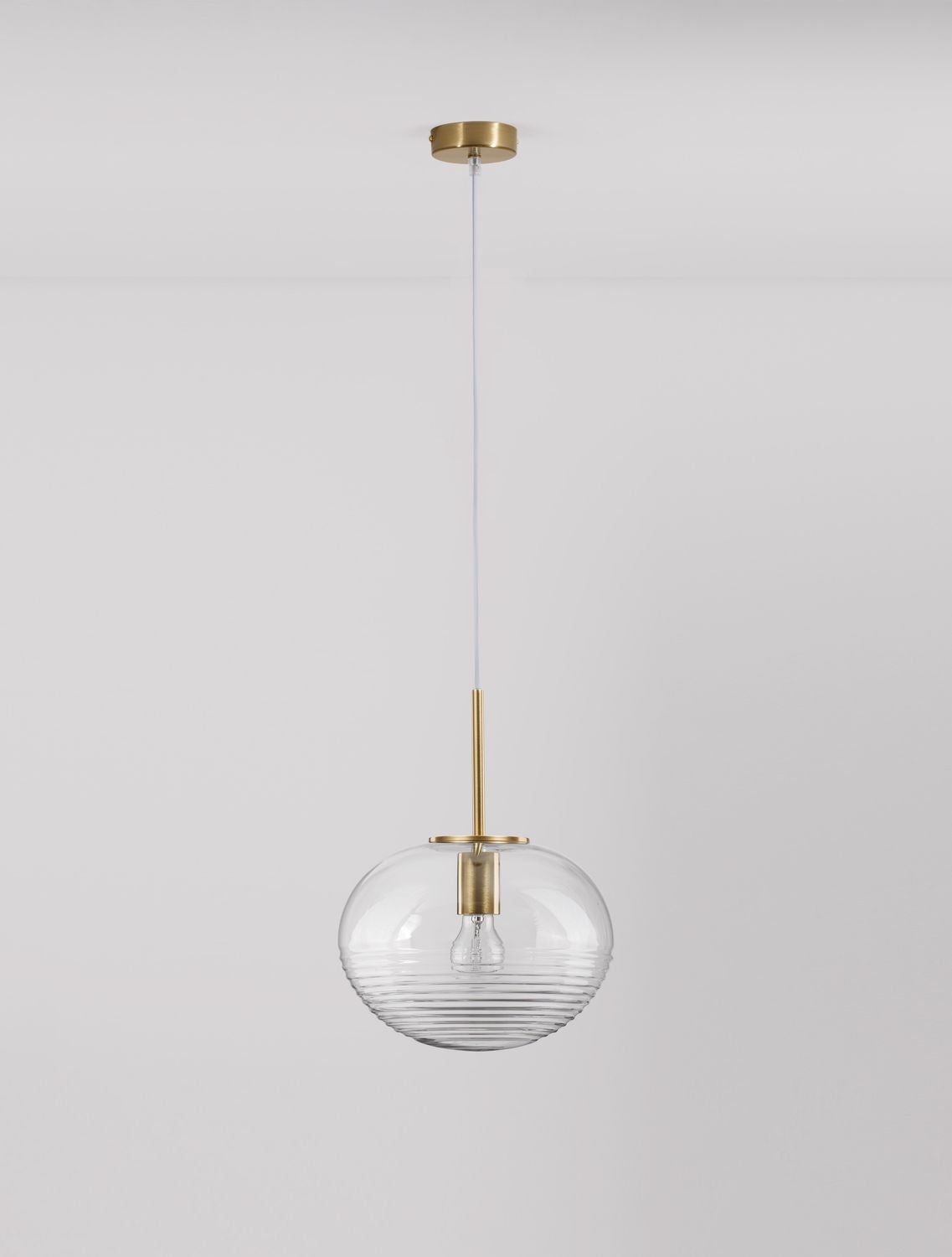 Suspension présentée de face sur mur gris clair, verre transparent et finitions en laiton doré