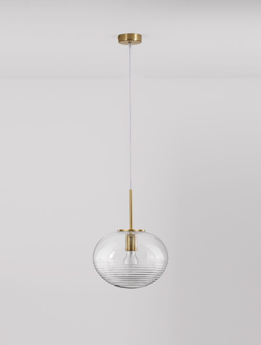 Suspension présentée de face sur mur gris clair, verre transparent et finitions en laiton doré