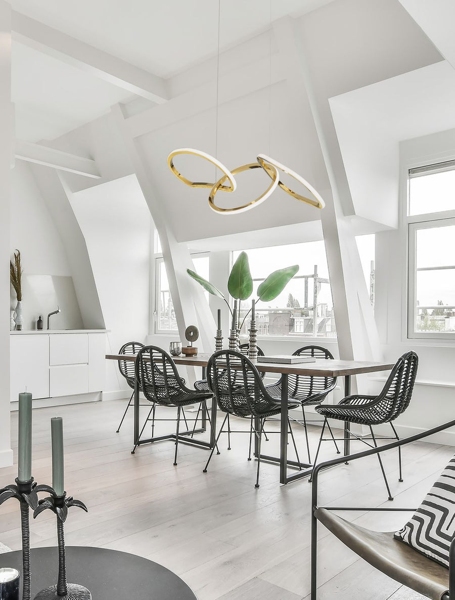 Suspension dorée à trois anneaux entrelacés au-dessus d'une table de salle à manger blanche