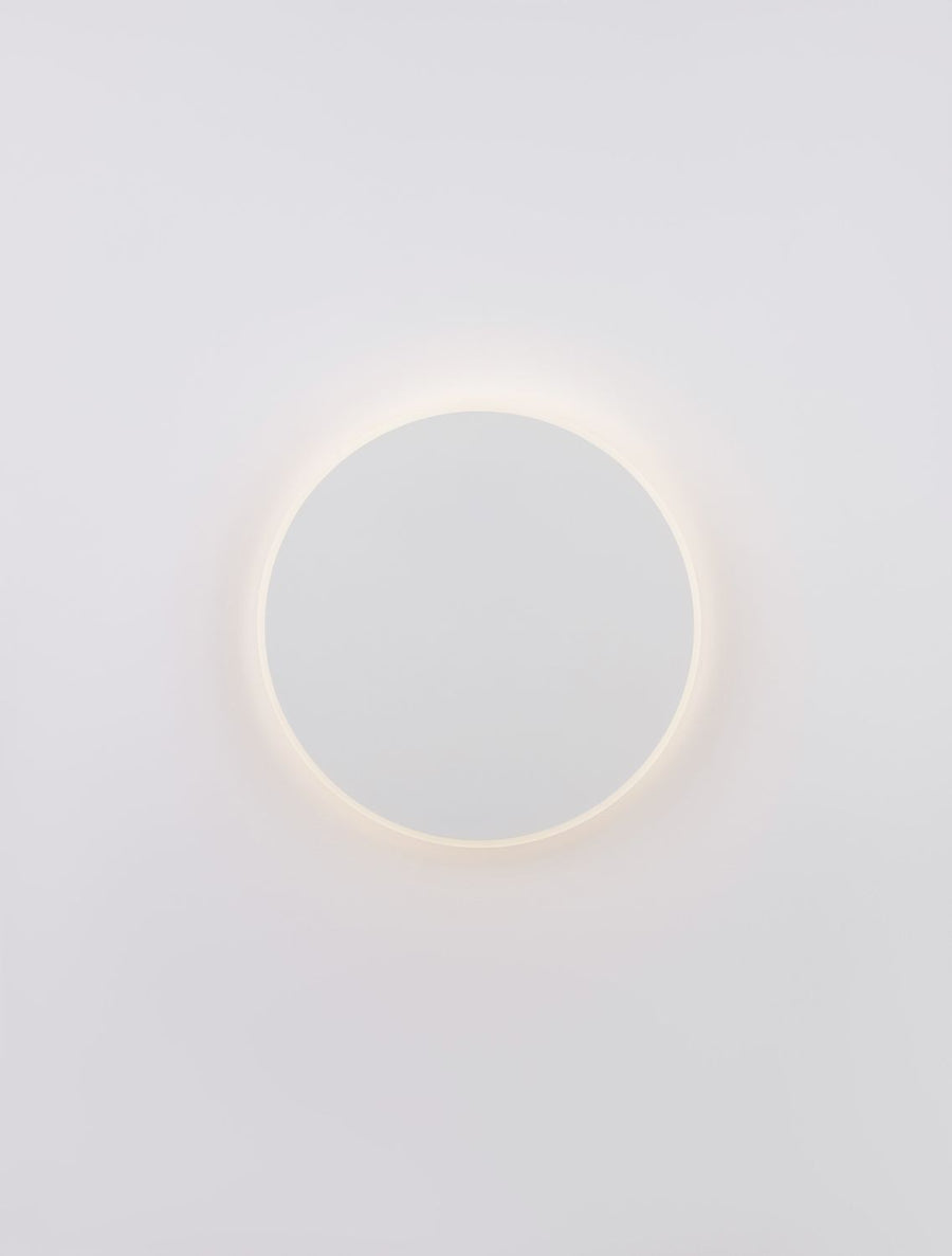 Applique ronde blanche éclairée de face, auréole chaude autour du disque