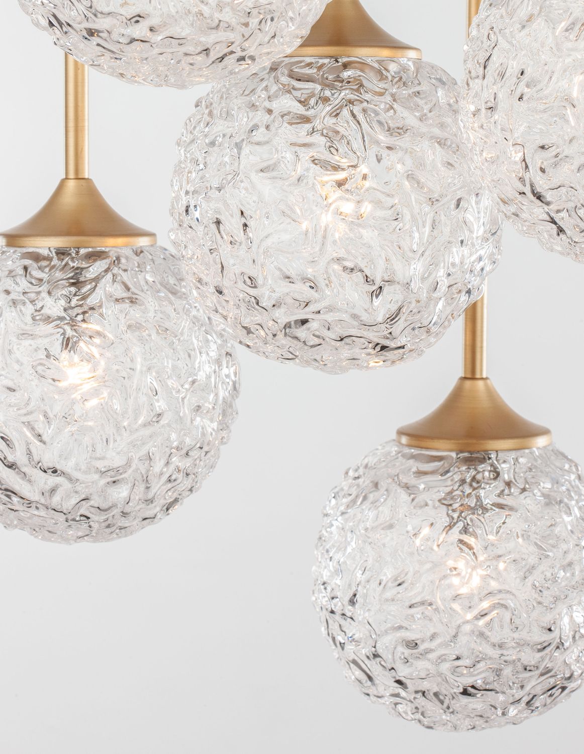 Gros plan sur plusieurs globes de verre transparent texturé suspendus par tiges dorées
