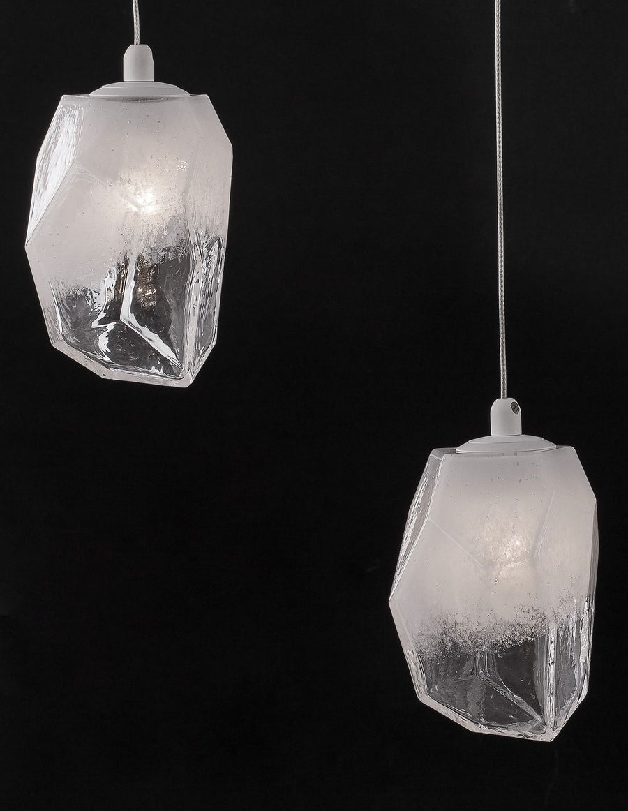 Deux suspensions en verre facetté éclairées sur fond noir, ampoules visibles.