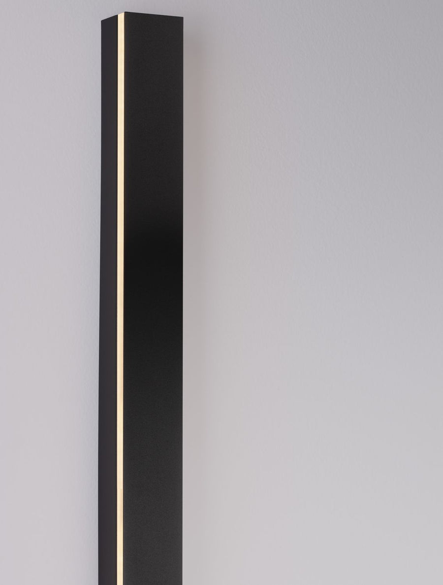 Détail de la face avant éclairée sur mur gris, diffuseur LED et corps noir mat