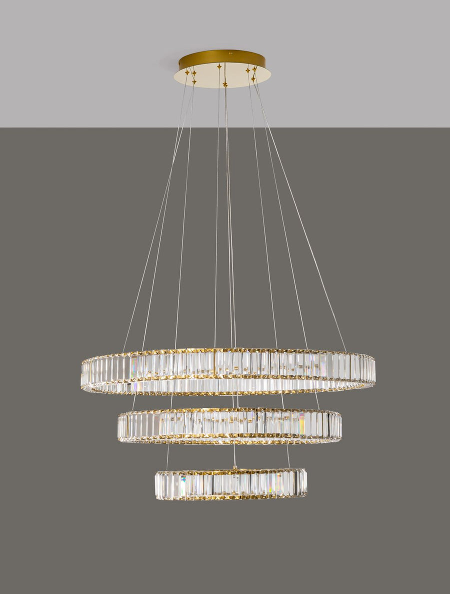 Luminaire allumé sur fond gris, câbles et rosace dorée bien visibles