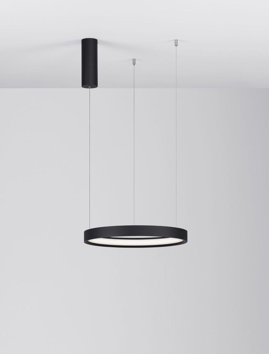 Suspension noire en anneau allumée, vue d'ensemble dans une pièce blanche