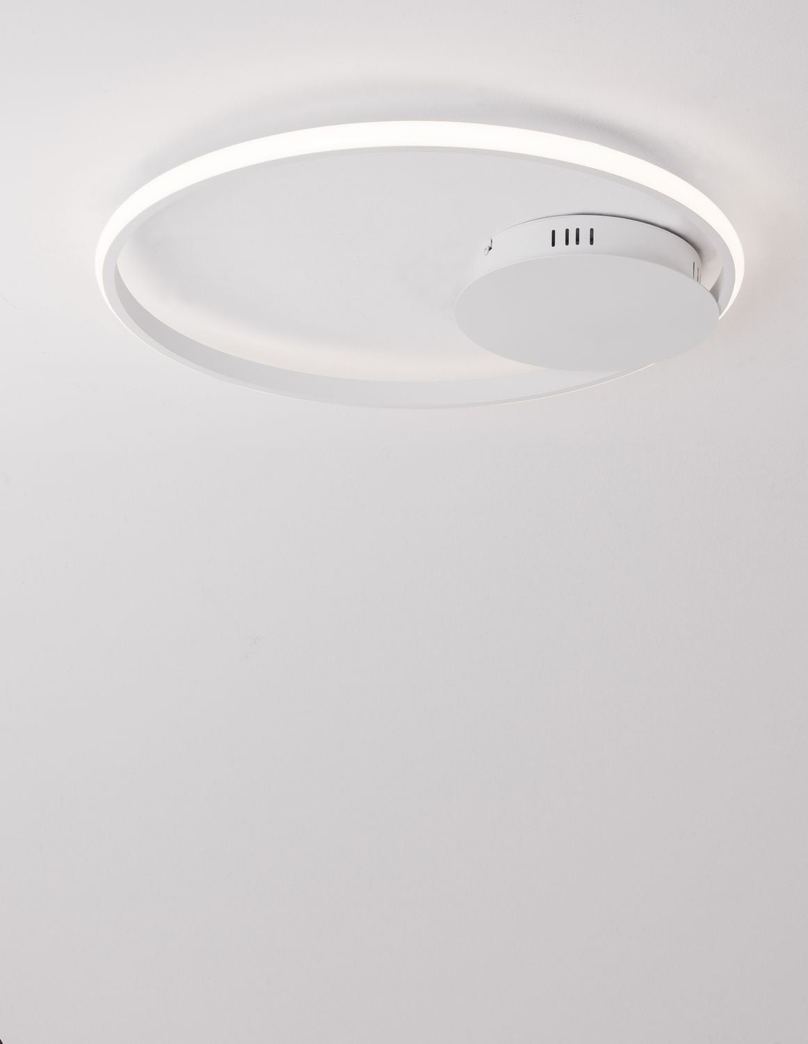 Luminaire allumé vu du dessous, anneau lumineux et boîtier avec grilles d'aération