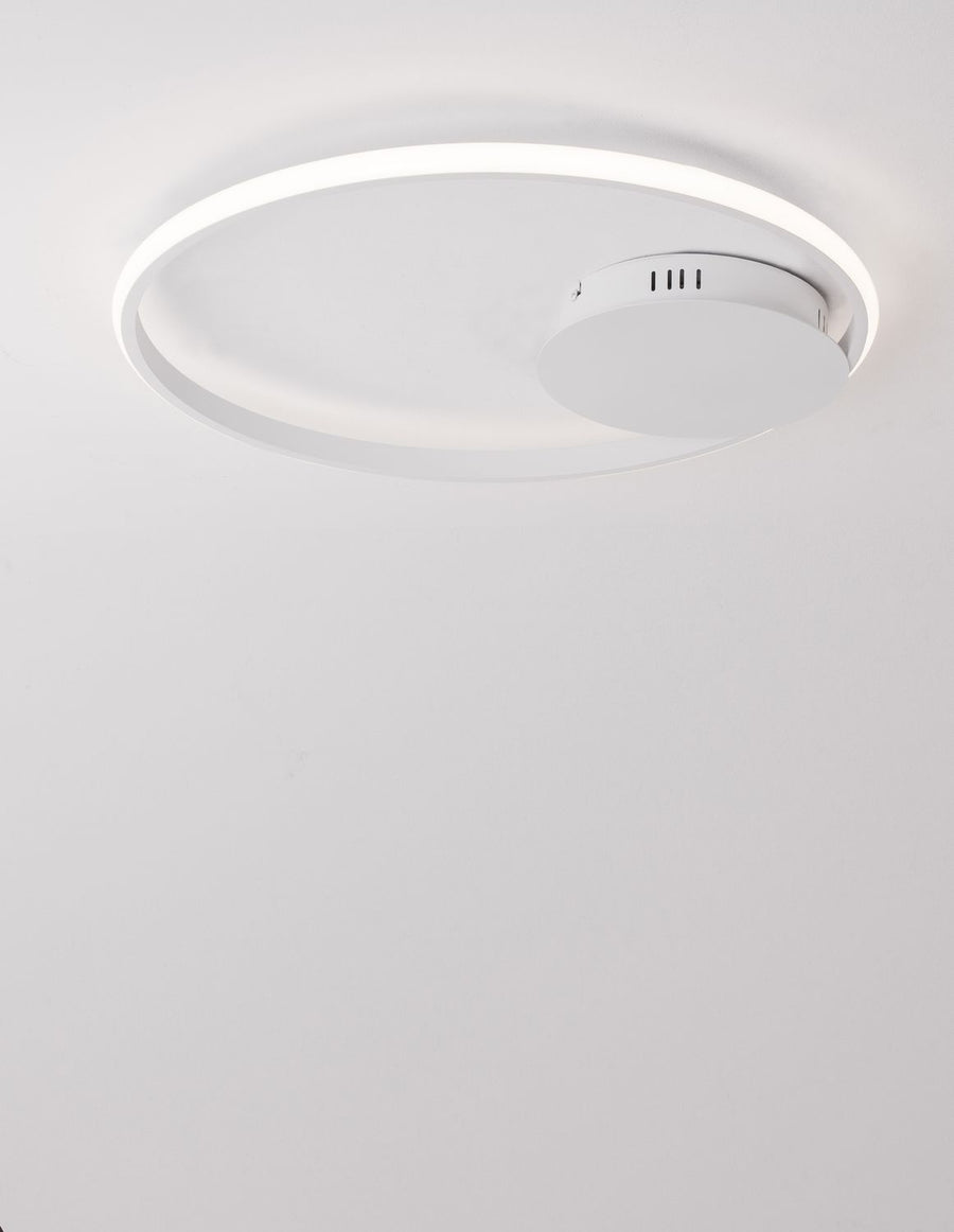 Luminaire allumé vu du dessous, anneau lumineux et boîtier avec grilles d'aération