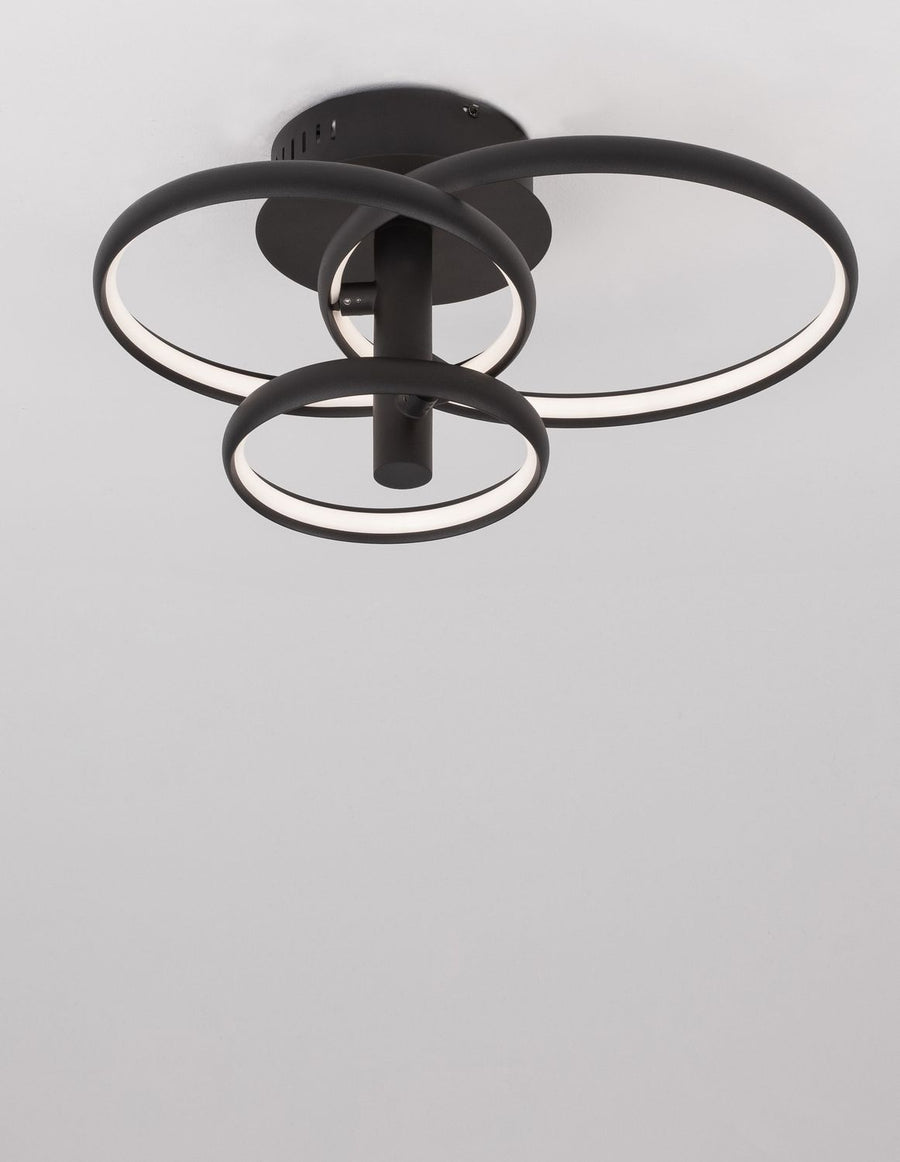 Luminaire allumé au plafond, anneaux lumineux diffusant une lumière blanche chaude