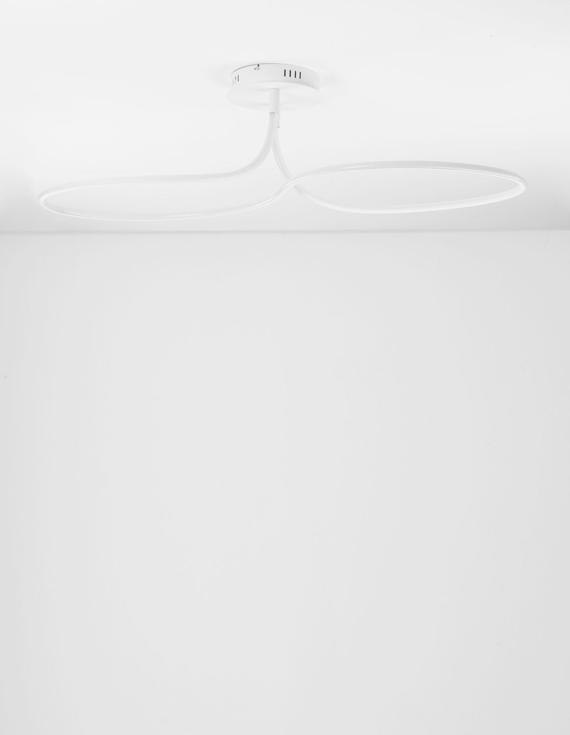 Vue plongeante du luminaire allumé, fixé au plafond blanc d'une pièce