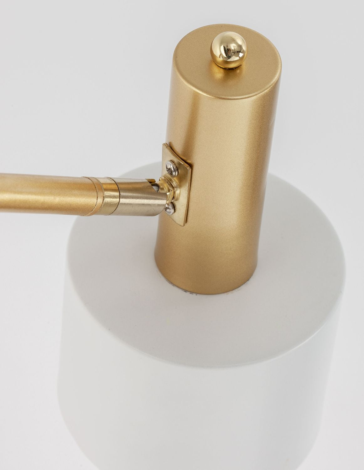Gros plan sur la fixation dorée cylindrique et la jonction métallique au-dessus de l'abat-jour.