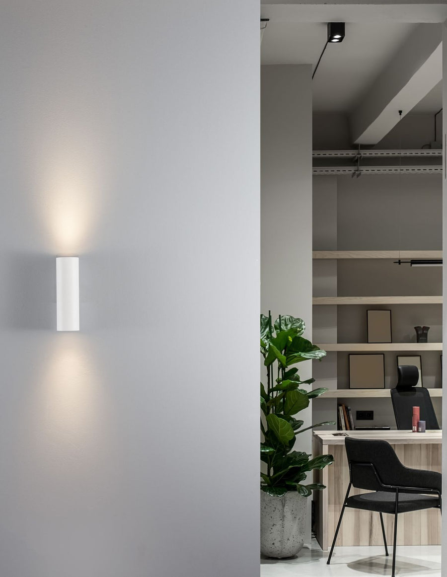 Applique murale blanche allumée, fixée sur un mur gris dans un bureau aménagé