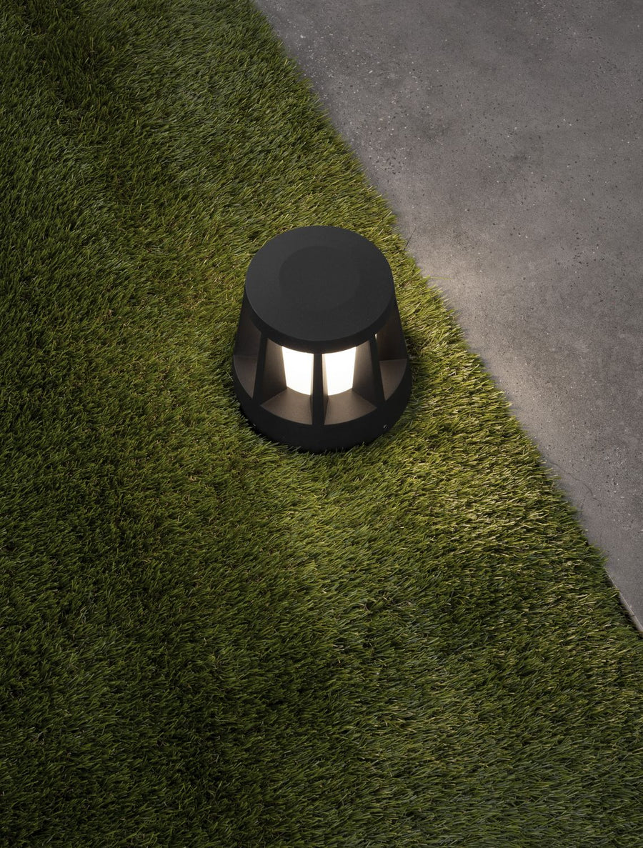Luminaire allumé sur la pelouse, lumière chaude diffusée vers le sol