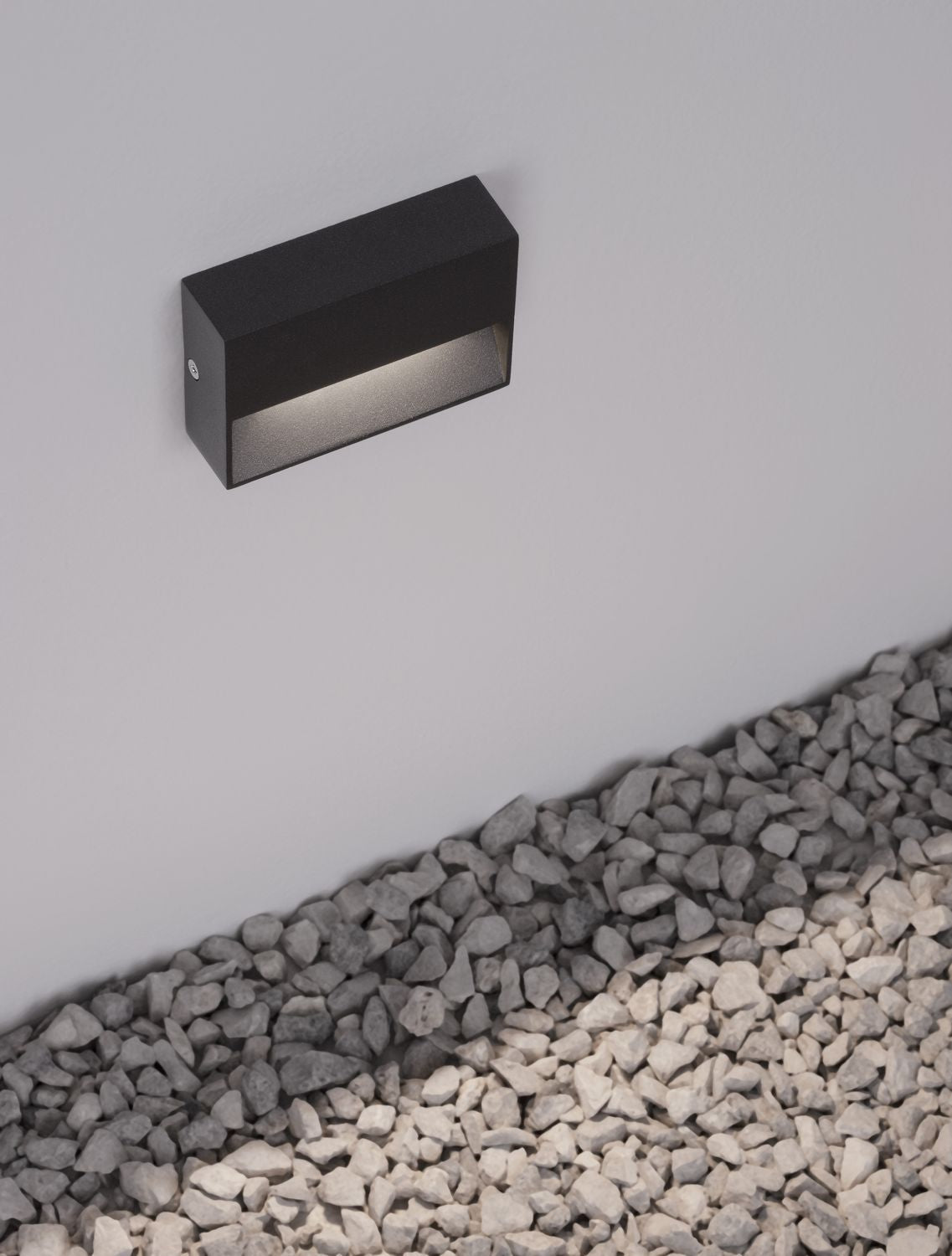 Vue rapprochée du luminaire mural anthracite allumé, détail de la finition et de la lumière.