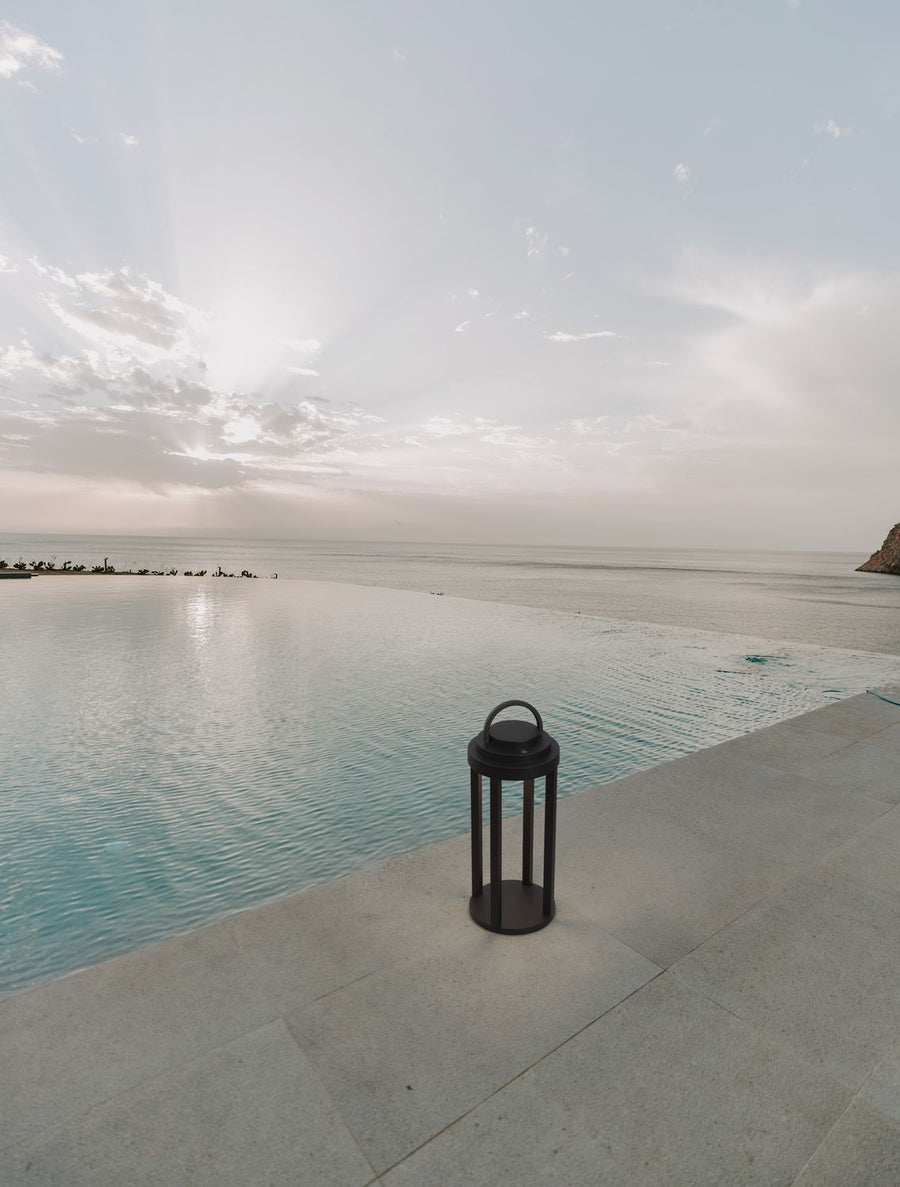 Lampadaire solaire posé au bord d'une piscine face à la mer