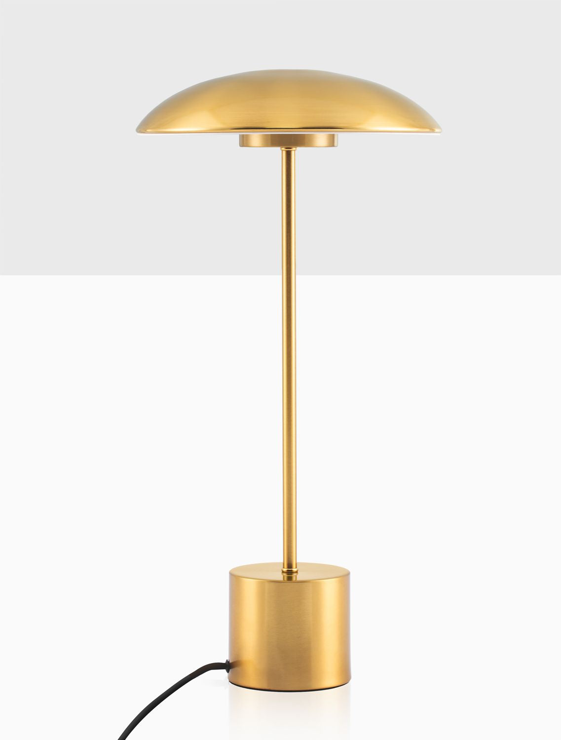 Détail du pied et du câble noir avec interrupteur, base dorée cylindrique.