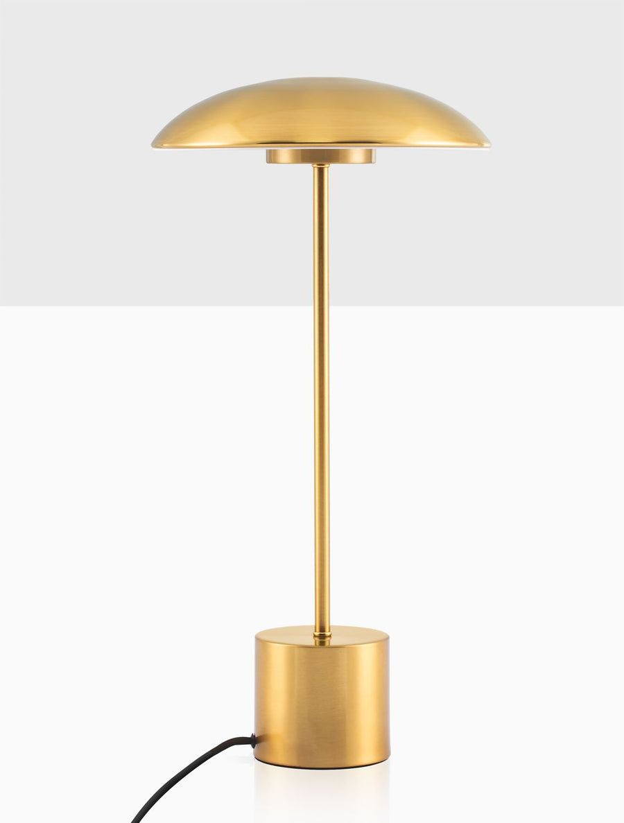 Détail du pied et du câble noir avec interrupteur, base dorée cylindrique.