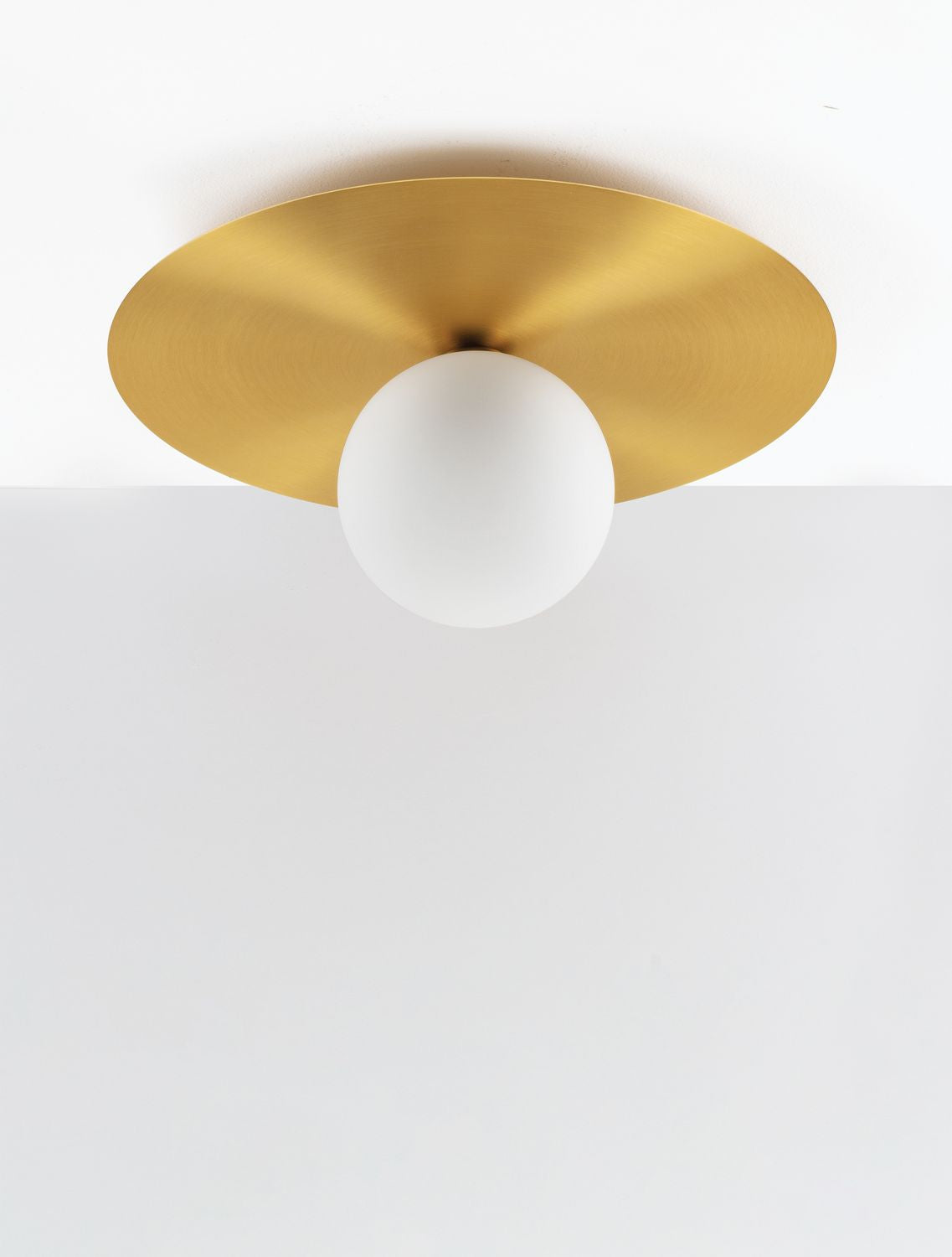 Plan serré sur le reflet doré du disque et la sphère blanche