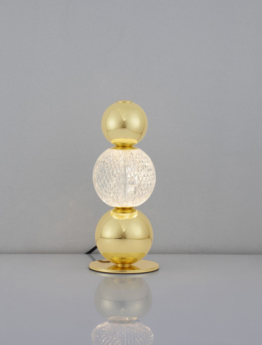 Lampe allumée sur fond gris, la sphère centrale en verre texturé diffuse la lumière