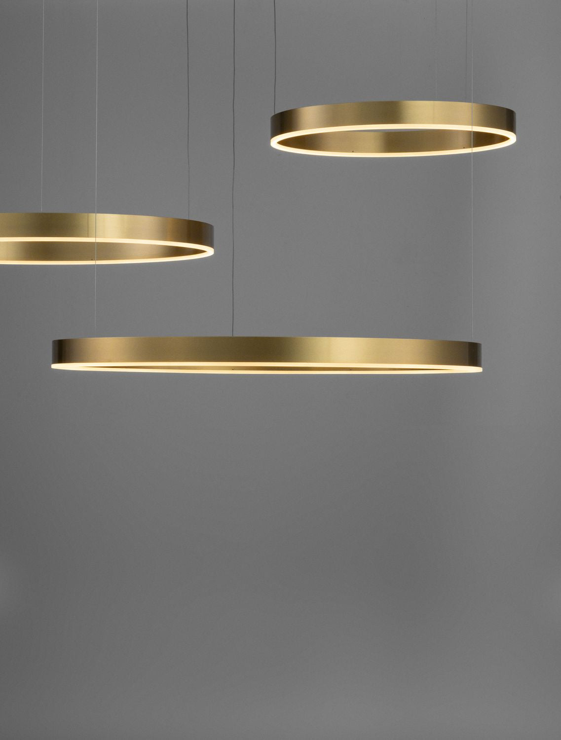 Détail rapproché des anneaux dorés éclairés par LED sur fond gris