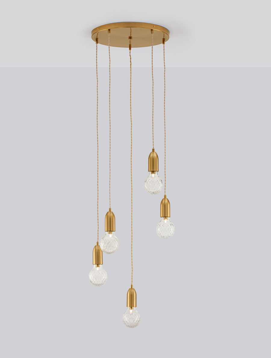 Même suspension allumée, cinq ampoules en verre texturé diffusant une lumière chaude