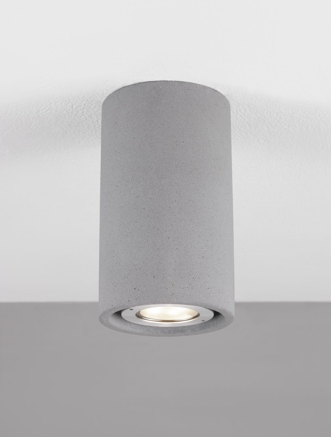 Luminaire installé au plafond, allumé, diffusant une lumière chaude par le verre inférieur.