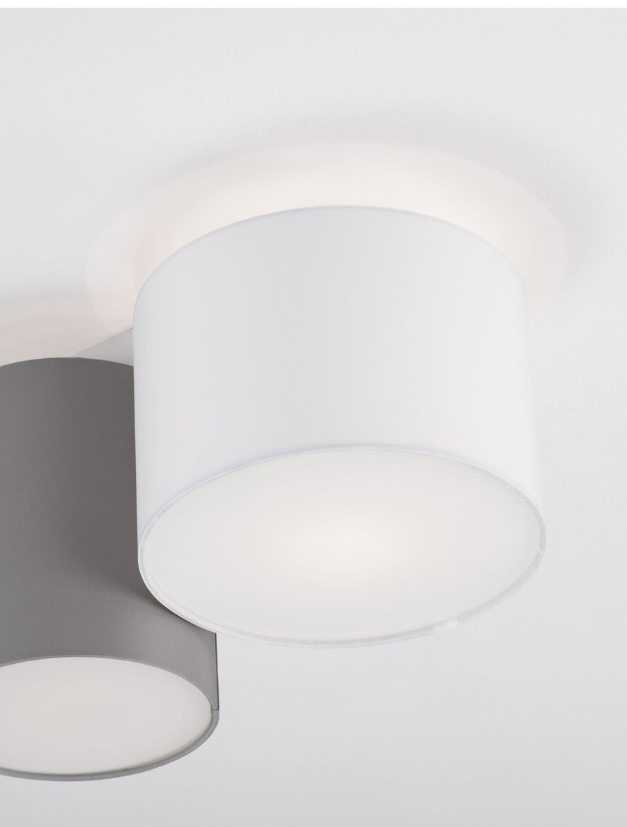Détail rapproché des abat-jours cylindriques gris et blanc sous le plafond